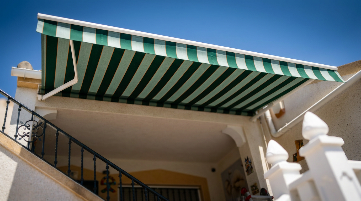 Toldo de lona verde y blanca instalado en una vivienda